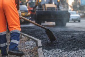 A,Male,Worker,Lays,Asphalt,Pavement,To,Repair,A,Road.