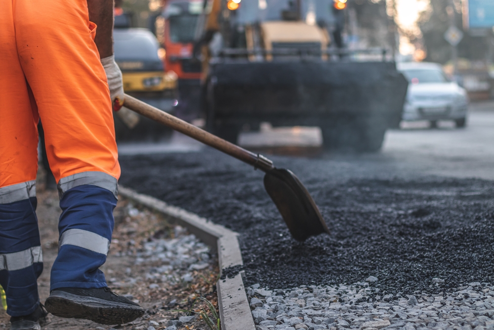 A,Male,Worker,Lays,Asphalt,Pavement,To,Repair,A,Road.