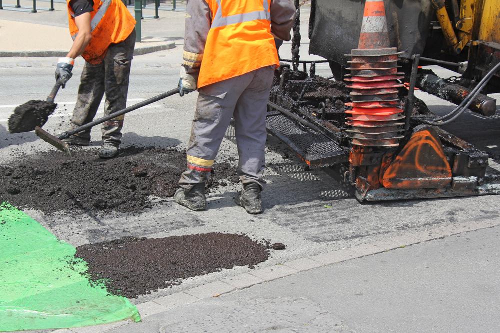 A group of workers shoveling asphalt onto a road